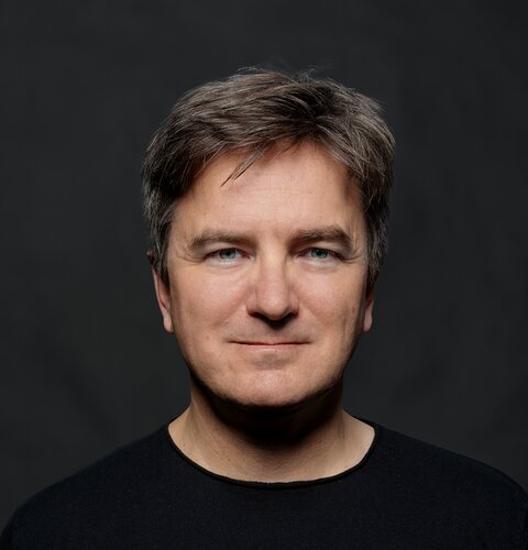 Matthias Specht | © wob AG Dieses Bild ist ein Porträt von Matthias Specht. Er trägt ein schwarzes Shirt. Der Hintergrund ist dunkel. | © wob AG