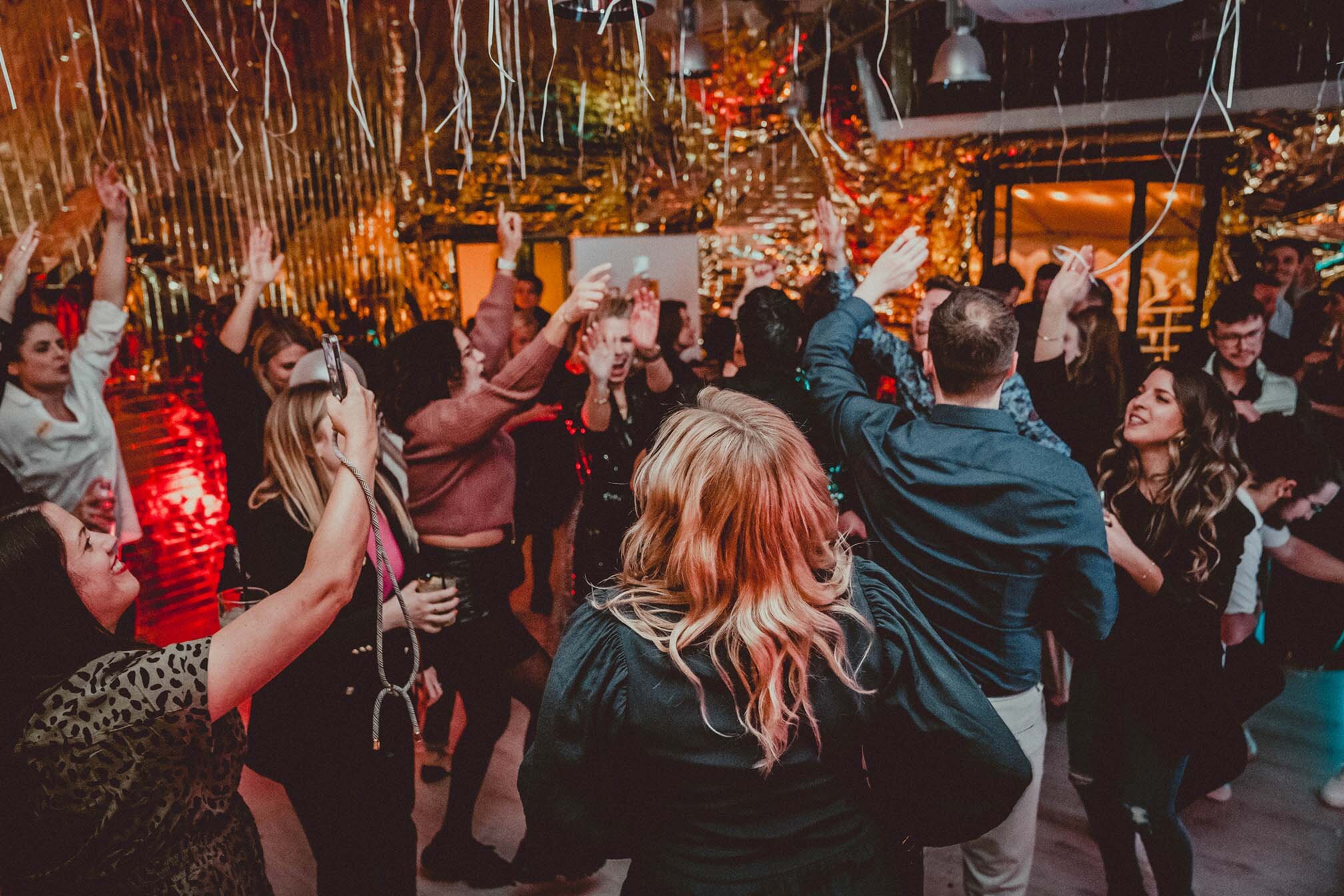 Das Bild zeigt eine Gruppe Menschen, die zusammen auf einer Tanzfläche feiern. Die Stimmung ist ausgelassen. Glitzernde Girlanden hängen von der Decke. | © wob AG