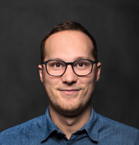 Das Bild ist ein Porträt von Thorsten Petersen. Er  hat eine Brille und ein hellblaues Hemd an. Der Hintergrund ist dunkel. | © wob AG