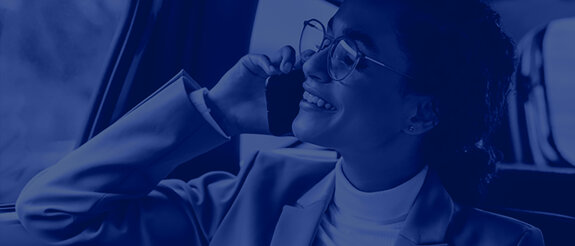 A woman in a suit and glasses can be seen in the crop, talking on the phone and gazing contentedly into the distance. A blue filter is placed over the image. | © wob AG